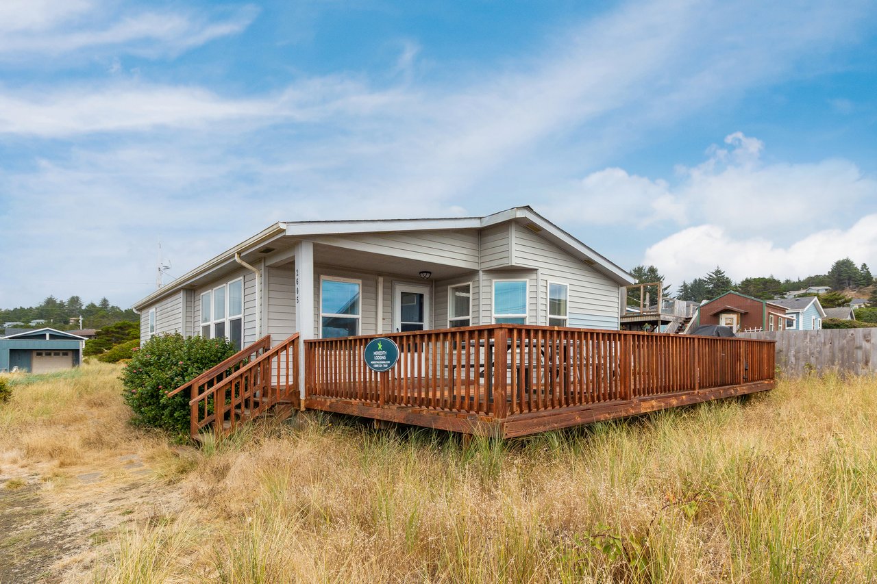This charming coastal retreat sits nestled among natural beach grasses, offering direct access to the shore with a spacious wrap-around deck perfect for savoring ocean breezes.