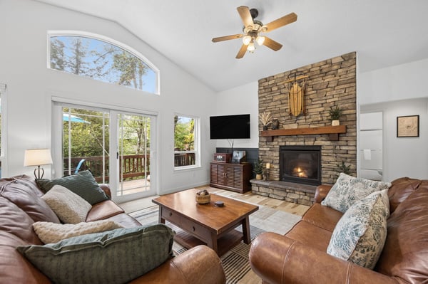 Relax in your spacious living room with a crackling fireplace and natural light streaming through the glass doors opening to your private deck surrounded by tall pines.