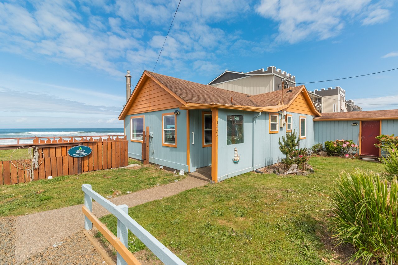 A charming beachfront cottage with ocean views, featuring manicured gardens and a private pathway leading to the sandy shore just steps away.