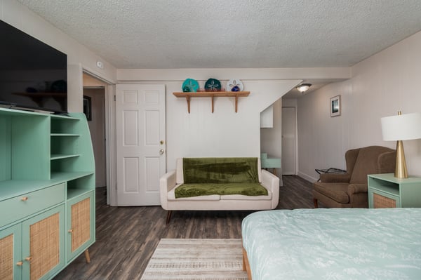 Your beachy retreat awaits with coastal colors, cozy seating, and thoughtful touches like the decorative sand dollars above the door—perfect for unwinding after your adventures.