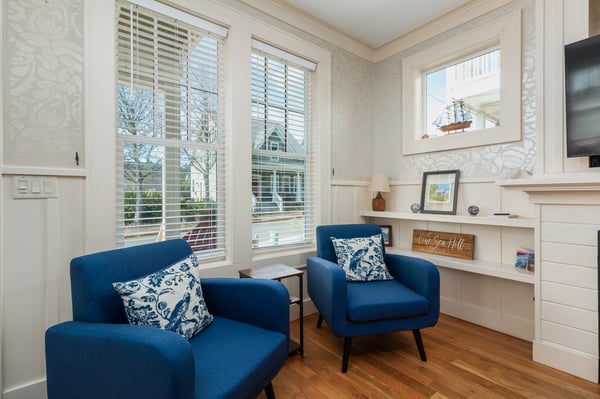Sink into plush navy armchairs with nautical touches, where built-in shelving and coastal artwork create your perfect reading nook.