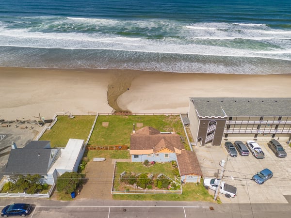 Stunning oceanfront property positioned directly on a sandy beach, offering rare direct beach access with waves lapping at the shore just steps from the back lawn.