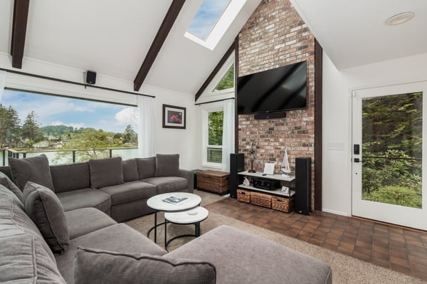 Sink into plush comfort as you take in stunning views through floor-to-ceiling windows. Natural light floods this cozy living room, complete with vaulted ceilings, exposed beams, and your own brick fireplace for those cool evenings.