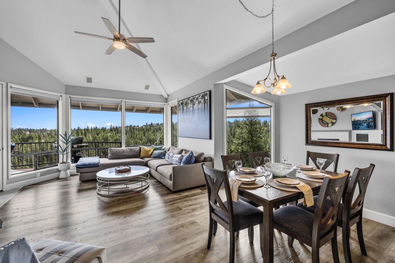 Relax in your light-filled living and dining area with soaring ceilings and sweeping forest views. Unwind on the plush sectional or gather around the elegant dining table—this space invites you to feel right at home.