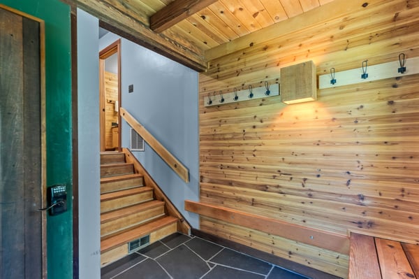 A warm welcome awaits at the entrance, featuring natural wood paneling, convenient coat hooks, and easy-access stairs leading you into your mountain retreat.
