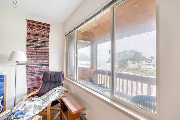 Unwind in your cozy reading nook, where a comfortable chair and footrest await beside large windows framing peaceful neighborhood views.