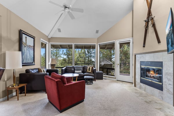 Unwind in your spacious living room with cozy fireplace and panoramic windows framing peaceful treetop views.