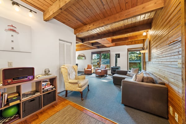 Relax in your cozy living space with soaring wood-beamed ceilings, warm natural light from large windows, and a wood-burning fireplace that adds rustic charm to your home away from home.
