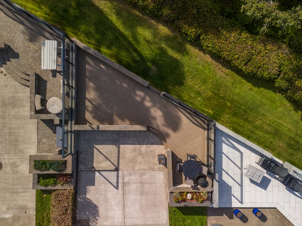 This aerial view captures the property's layout, showcasing a private patio, lush green lawn, and surrounding trees that create a peaceful retreat.