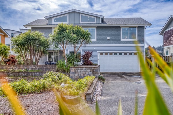 Coastal contemporary home features distinctive architecture with mature palm trees and thoughtfully designed landscaping in a quiet residential neighborhood.