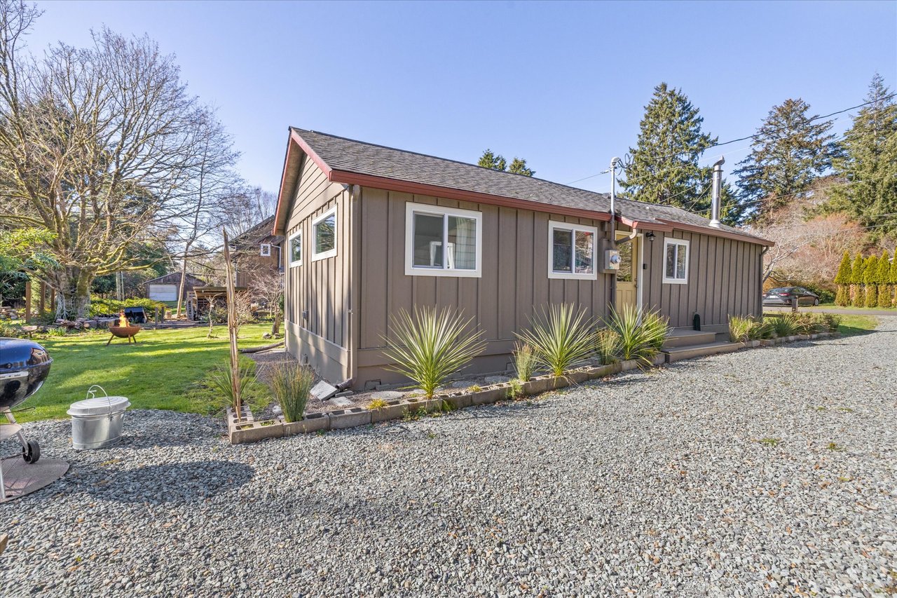 Charming single-story home with modern landscaping, surrounded by mature trees in a peaceful neighborhood setting.
