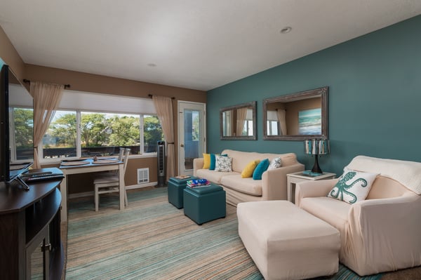 Settle into the comfortable living area where cheerful accents and natural light create a welcoming atmosphere. Relax on plush seating, enjoy meals at your dining table, and soak in tree-lined views from the window.
