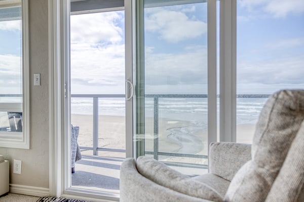 Your oceanfront escape awaits with floor-to-ceiling windows framing endless beach views from your cozy living room.