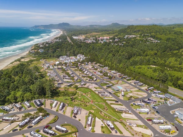 Aerial view of a coastal vacation resort community nestled between ocean and mountains, with direct beach access and scenic natural surroundings.