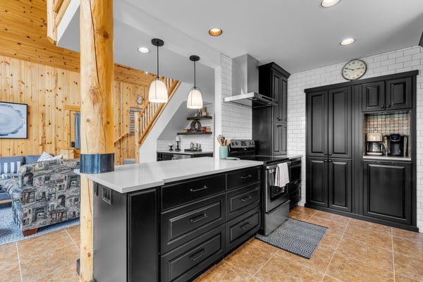 Picture yourself creating meals in this fully-equipped kitchen with sleek dark cabinetry, white subway tile, and a spacious island—perfect for gathering and cooking during your mountain getaway.