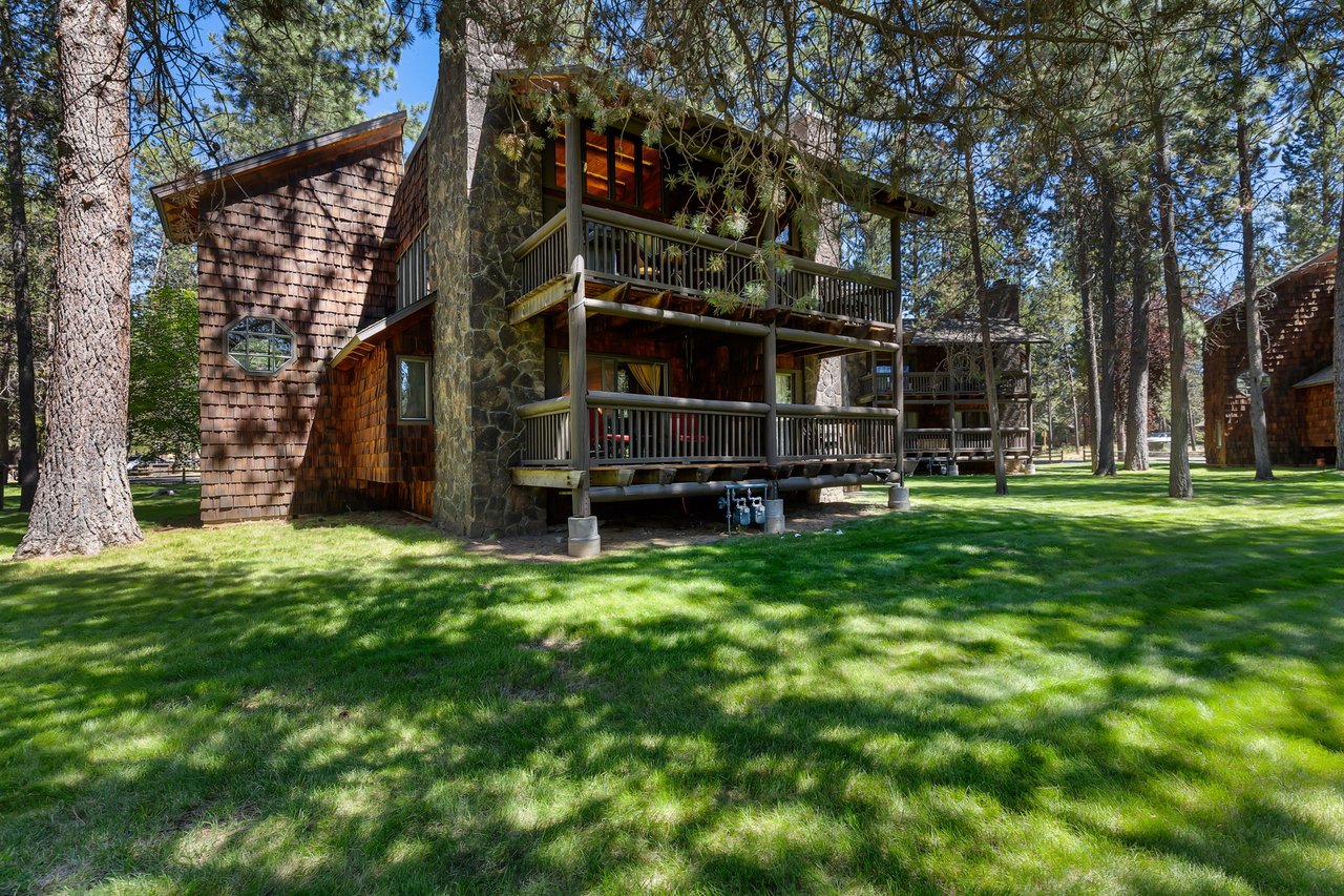 This charming rustic cabin stands amid towering pines and lush green lawns, offering a peaceful forest retreat with dual-level balconies perfect for morning coffee and starlit evenings.