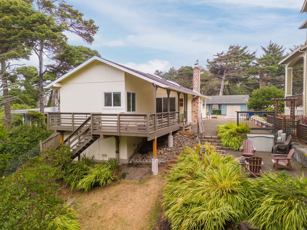 Charming beachside cottage with wraparound deck, hot tub, and lush coastal gardens nestled among tall pines—perfect for your relaxed Oregon getaway.