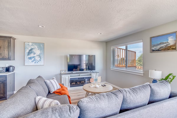 Sink into plush seating and unwind in your bright, coastal-inspired living space, where a cozy fireplace and scenic mountain views create the perfect retreat.