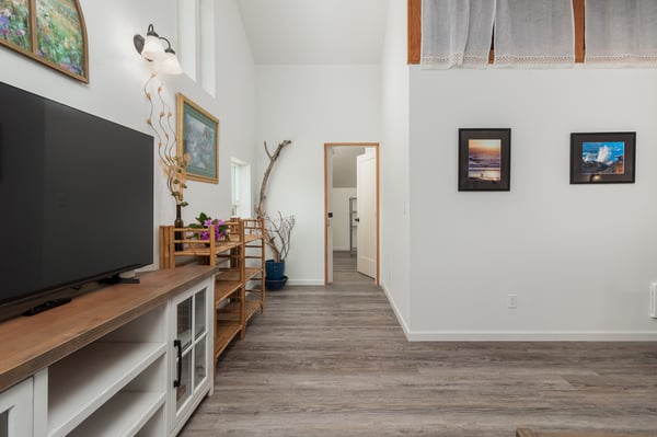 Bright and spacious living room with warm wood tones, thoughtful decor, and a large TV for your downtime. Vaulted ceilings and plenty of natural light create an inviting space to relax.