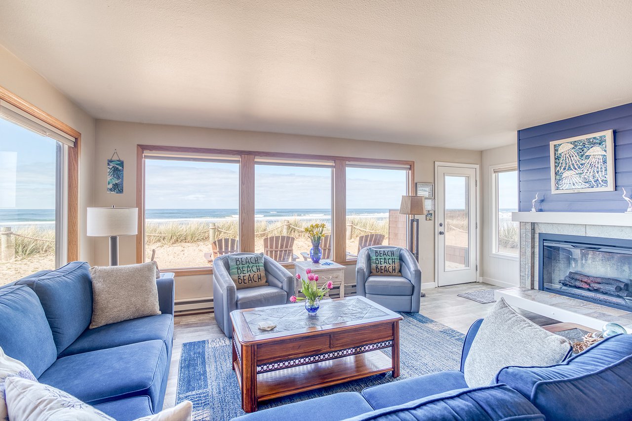 Sink into plush blue sofas while ocean waves roll just beyond your windows, creating the perfect beachfront retreat.