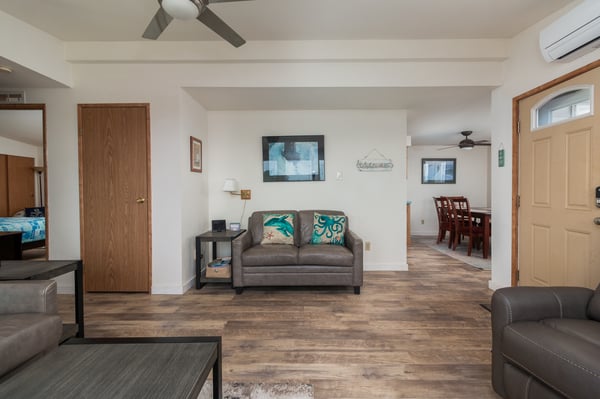 Bright, open living space with ceiling fans and air conditioning. Plush sofas, dining area, and bedroom flow together seamlessly for ultimate comfort and relaxation.