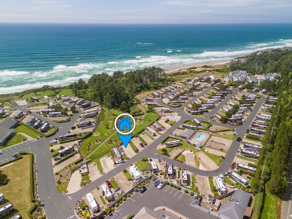 Aerial view of a coastal vacation rental community nestled between lush forests and pristine beachfront, with property location clearly marked.