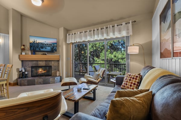 Sink into the plush sofa as the fireplace crackles nearby, warming your space with a cozy glow. Beyond the glass doors, your private balcony overlooks lush greenery—the perfect spot to unwind and breathe in the fresh mountain air.