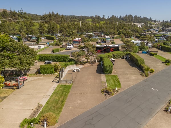 Aerial view of the property and its tree-lined neighborhood, surrounded by coastal hills and forested landscapes.