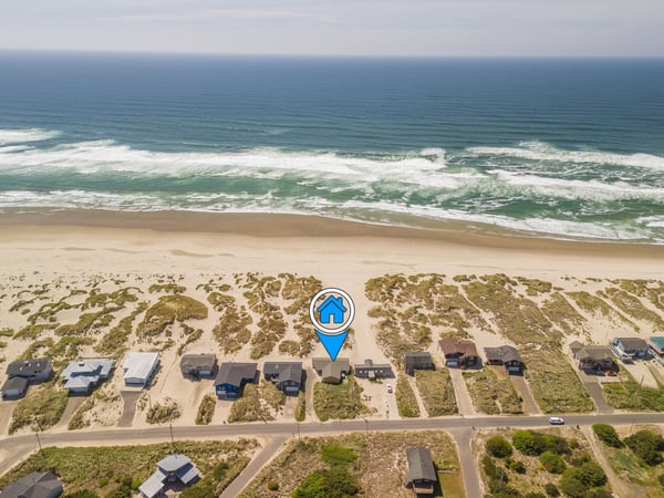 Aerial view showcasing the property's prime beachfront location, nestled between sandy dunes and the ocean, with easy access to the waterfront.
