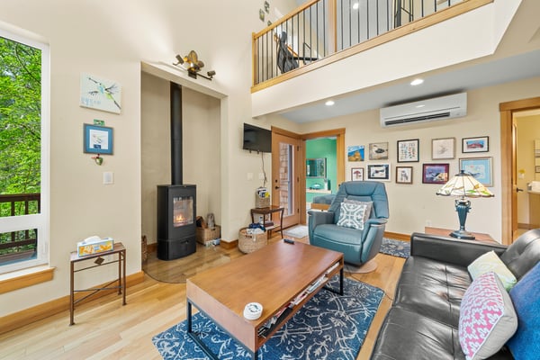 Settle into your inviting living room where high ceilings and warm wood floors create a bright, airy retreat. The cozy fireplace and comfortable seating make it your perfect spot to unwind.