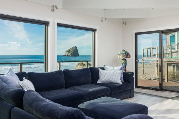 Sink into plush navy sectionals while watching waves crash against iconic offshore rock formations through floor-to-ceiling windows.