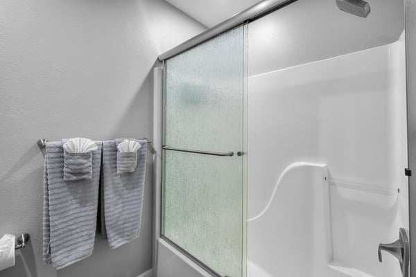 Your private bathroom features a spacious shower with frosted glass doors and fresh towels waiting for you, creating a serene space to refresh after a day of exploring.