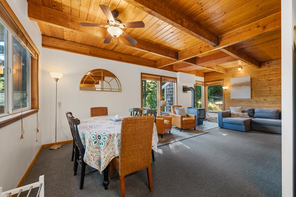 Gather around the dining table under warm wooden beams while sunlight filters through large windows. The open layout flows into a comfortable living space, perfect for unwinding after your day's adventures.