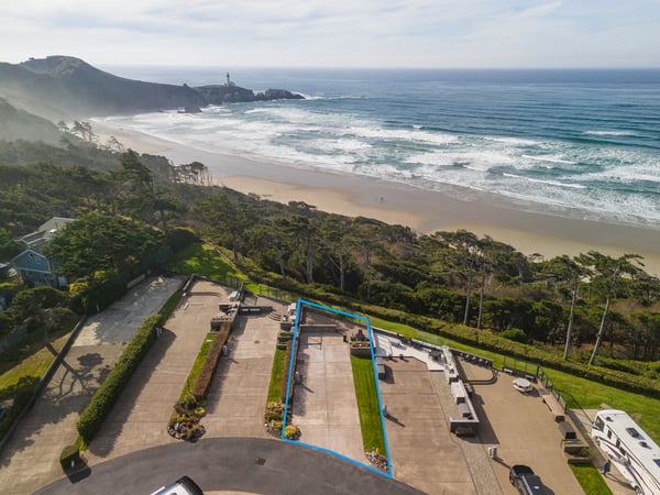 Aerial view showing the property's coastal location, with a pristine sandy beach and dramatic ocean waves just beyond the lush natural surroundings.