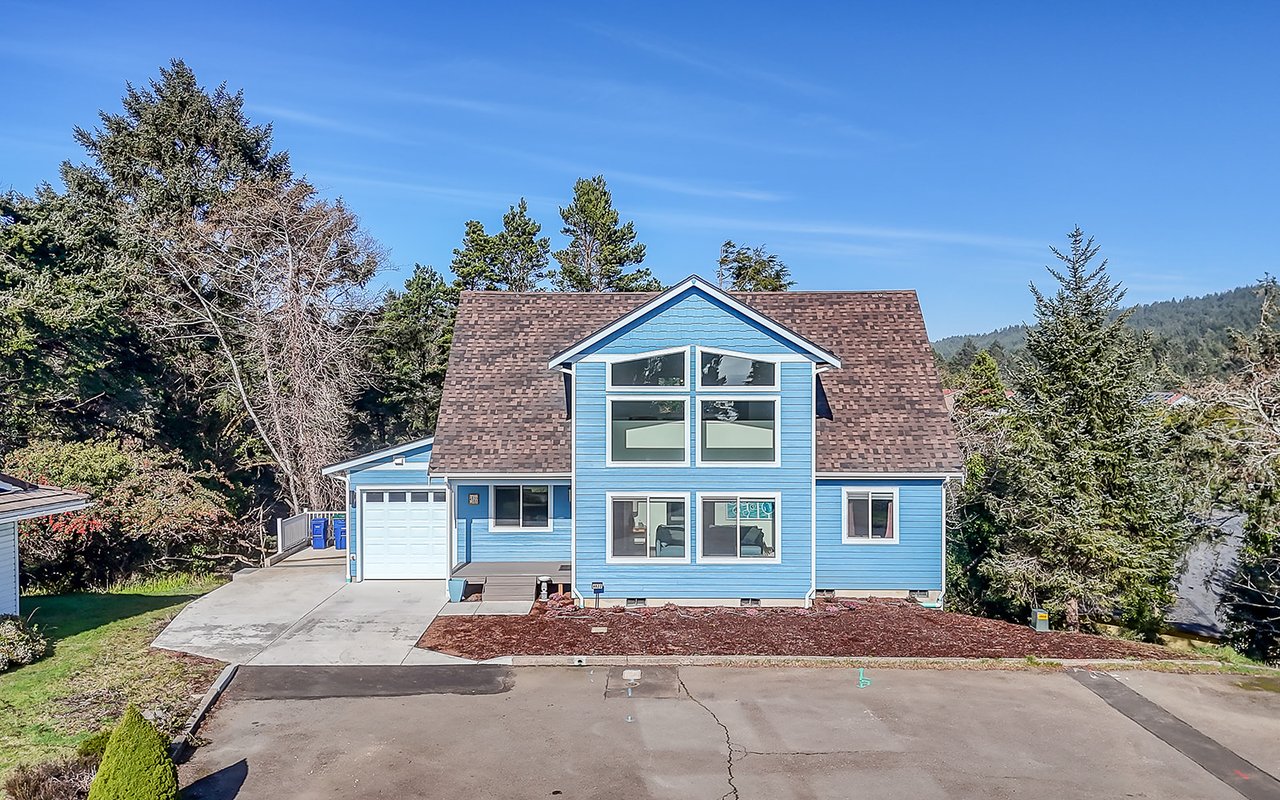 Charming blue vacation home nestled among towering evergreens with mountain views and spacious parking for your getaway.