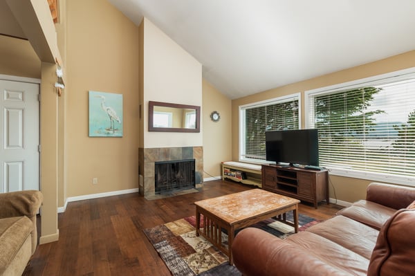 Unwind in your spacious living room with leather seating, warming fireplace, and natural light streaming through large windows.