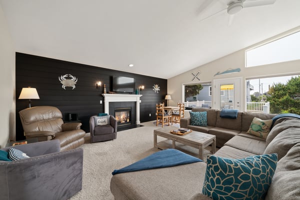 Sink into plush seating by the warm fireplace, or gather around the dining table as natural light fills your coastal retreat through the bright glass doors.