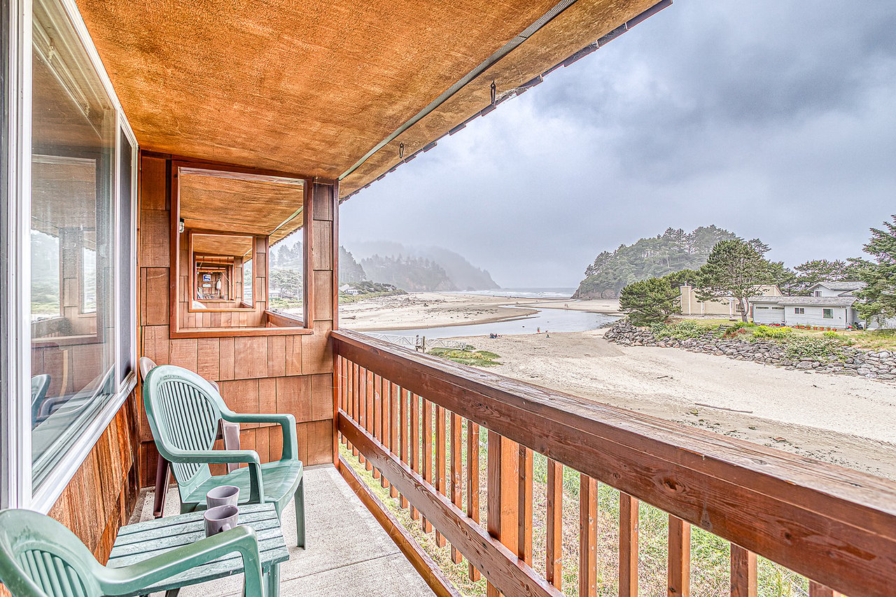 The property offers a covered balcony with seating overlooking a scenic beach and coastal landscape, providing a serene spot to enjoy the ocean views and natural surroundings.