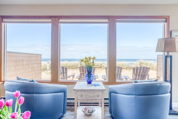 Unwind in your coastal retreat where blue leather chairs face stunning ocean views through oversized windows.