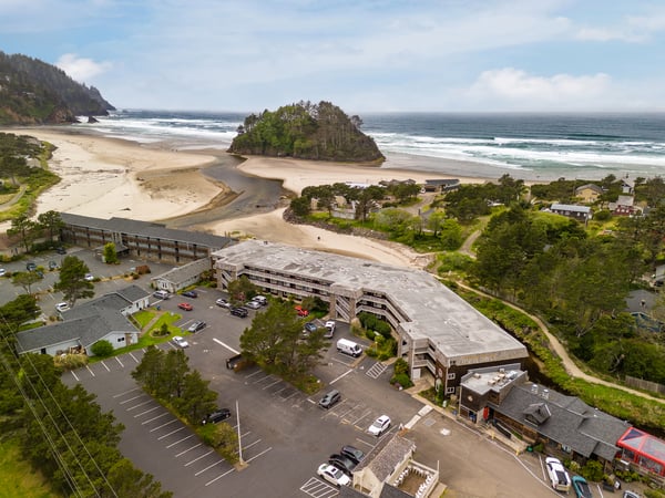Aerial view of the beachfront property nestled between dramatic coastal headlands and pristine sandy shores, with direct access to scenic natural surroundings.