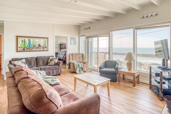 Sink into plush seating with ocean views streaming through expansive windows, where coastal charm meets comfort in your perfect retreat.