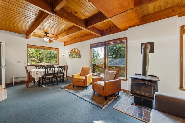 Relax in your cozy living area with vaulted wood ceilings, a warming fireplace, and inviting leather seating that opens to a sun-filled dining space—perfect for unwinding after a day of adventure.