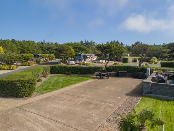 An RV park nestled among coastal trees and manicured landscaping, featuring spacious pads and well-maintained grounds under open skies.