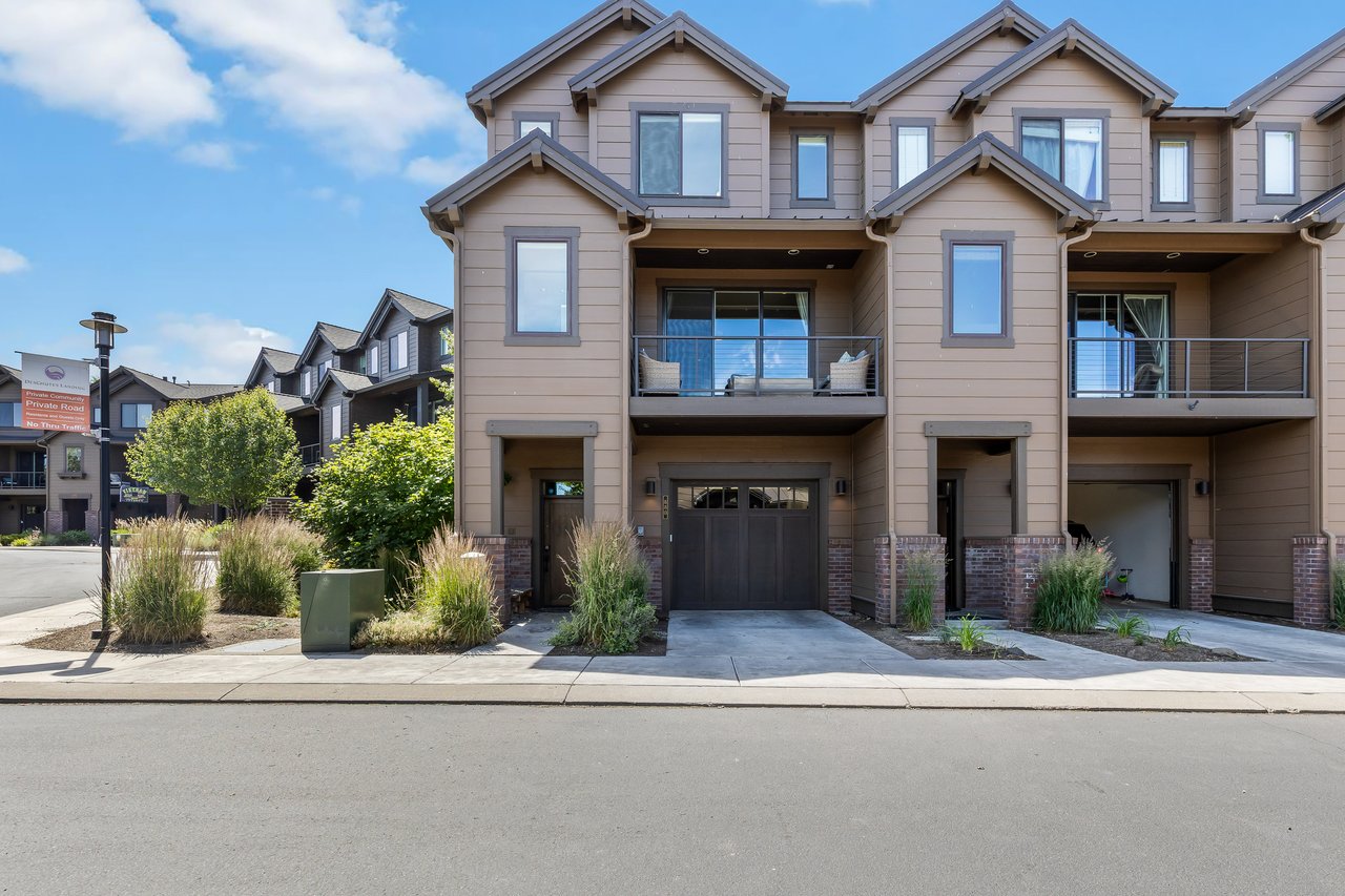 Modern townhome exterior featuring private garage, covered balcony, and drought-resistant landscaping in a quiet residential setting.