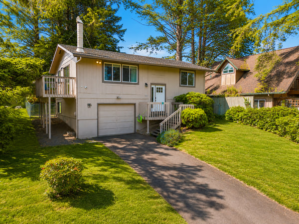 A sunny retreat surrounded by lush greenery and mature trees in a peaceful neighborhood. The well-maintained lawn and landscaped garden create a welcoming arrival at this private getaway.