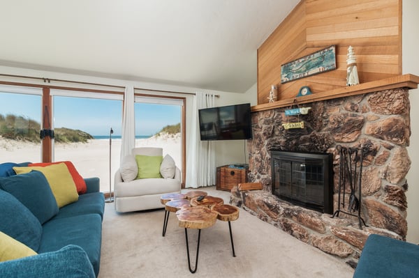 Your cozy beachfront retreat features a charming stone fireplace, vibrant seating, and stunning sand dune views just steps from your door.