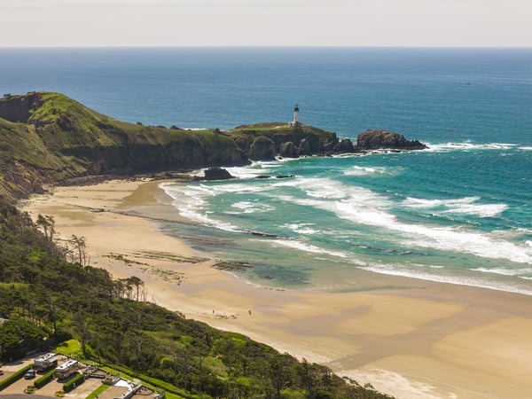 Scenic coastal area near the property featuring sandy beach, turquoise waters, green hillsides, and a historic lighthouse on rocky cliffs overlooking the Pacific Ocean.