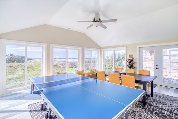 Your game room features ping-pong fun with sweeping coastal views through panoramic windows, perfect for friendly matches.