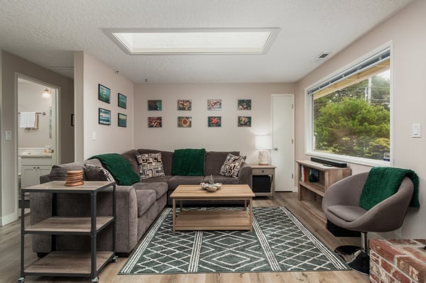 Unwind in your bright, modern living room with cozy seating, natural light streaming in, and views of lush greenery that bring the outdoors right to your doorstep.