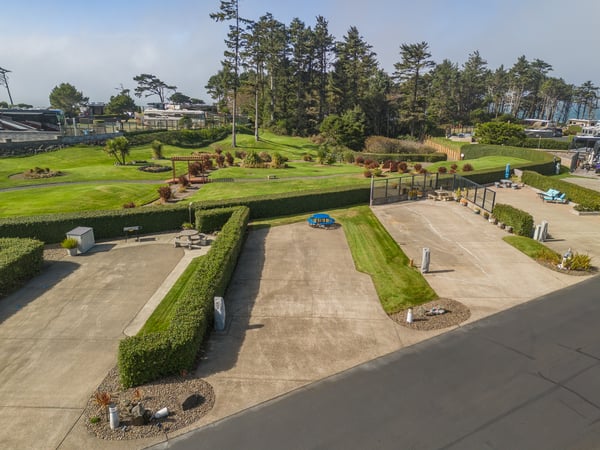 The property features expansive landscaped grounds with manicured lawns, tall pines, and nearby coastal access—a peaceful retreat offering outdoor space and natural beauty.